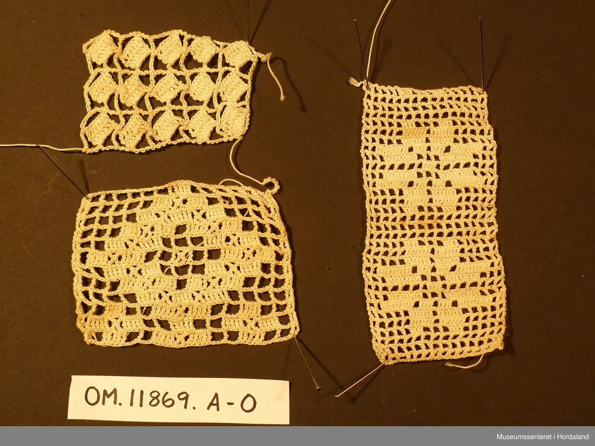 Denne gruppa er samasett av 13 små lappar. 10 av dei er like og er nok tenkt sett saman til eit større arbeid. Dei 3 andre er prøvar på ulike mønster. Ein liten rest på eit garnnøste fylgjer med, samt eit heklemønster klipt ut frå eit ukeblad.