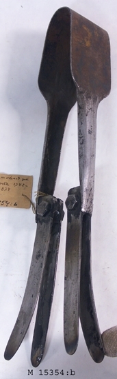 Dubbelsax/bockhornssax (skärsax) av järn för 
skärning av en specifik typ av ben på vinglas, 
där benet har en "ås" eller "knapp" på mitten. 
Se M 15354:A.
Föremålet är en rekonstruktion från 1941 av ett 
verktyg som användes på Kosta glasbruk 1742-
1874. 
Verktyget består av ett på mitten böjt plattjärn som 
utgår i två ben med innåtböjda kanter (vilket bildar 
verktygets handtag). På handtagens nedre del sitter 
fyra järnblad (två par) fästa.
Inskriven i huvudkatalogen 1942.

Finns på Smålands museum, basutställningen 
"På väg" 1800-tal, 2006-08-23
Funktion: Att skära glas