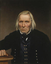 Portrett av Omund B. Birkeland. Mørk drakt med stripet vest, hvit skjorte og svart halsbind. Hviler høgre hånd på et bord. (Foto/Photo)