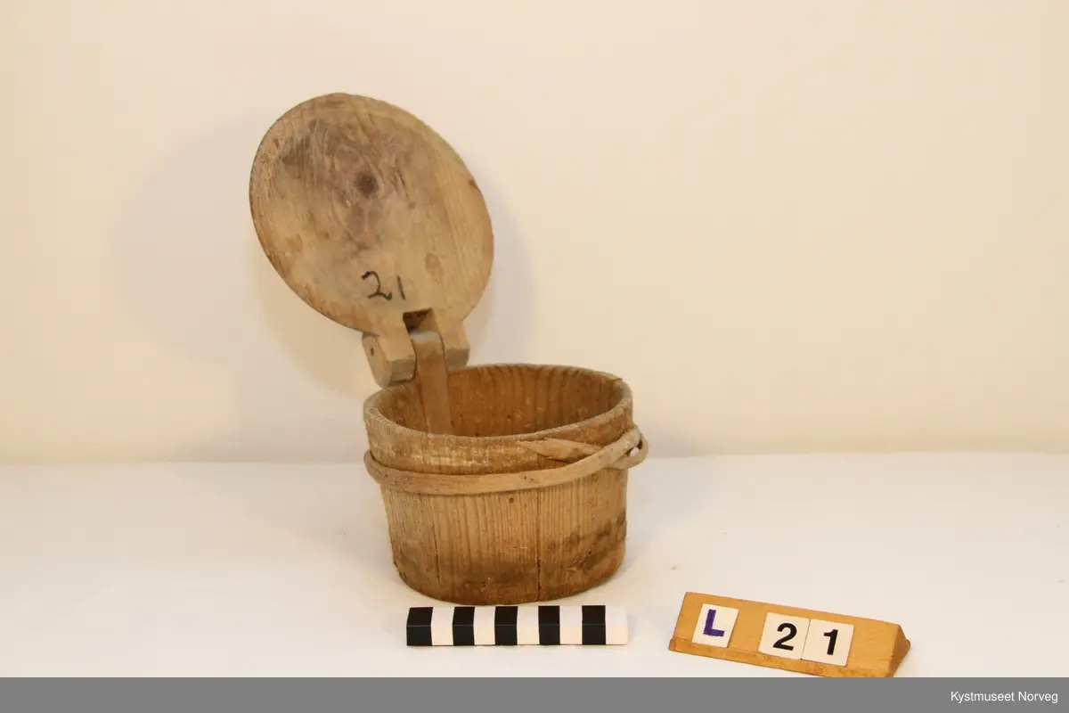 Smørkoppen er brukt til oppbevaring av smør. Treband; to nederst og et øverst. På lokke hank av jerntråd.