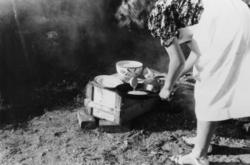 Sara Grønvik steker pannekaker utendørs.  1944