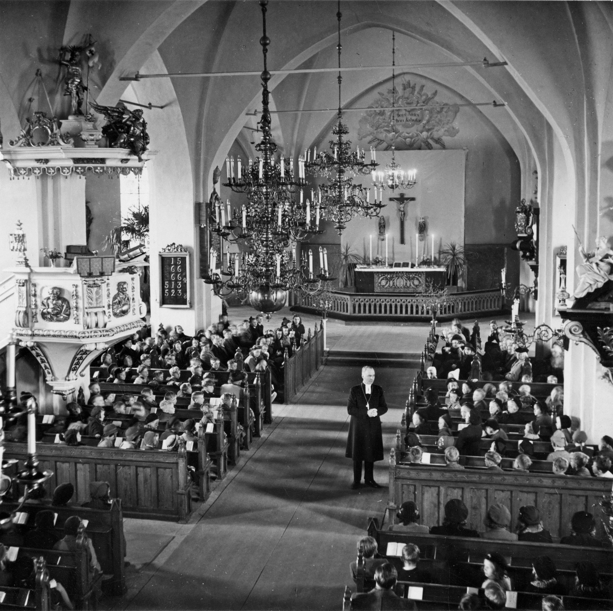 Kyrkoherde Gustav Gustavsson med församling inne i Köpings Kyrka.
