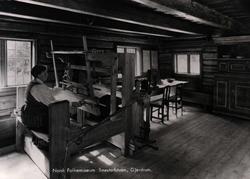 Postkort. Smestadstuen, Gjerdrum på Romerike. Kvinne ved vev