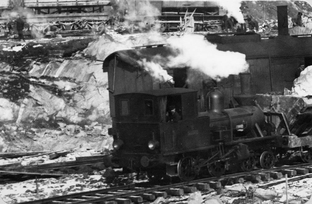 Dette skiftelokomotivet hadde navn "Bifrost". Loket fikk senere et LKAB-nummer 5.  Loket står nå plassert på Narvik stasjon.     Överst i bilden skymtar en treaxlig tippvagn och ett tidigare FLJ-lok. Därnäst en ångdriven grävmaskin samt Bifrost under växling av tippvagnar med dodbuffertar.
    Dödbuffertar, tidigare vanligen skrivet dödbuffrar, är ofjädrade och förekom även på SJB schaktvagnar.