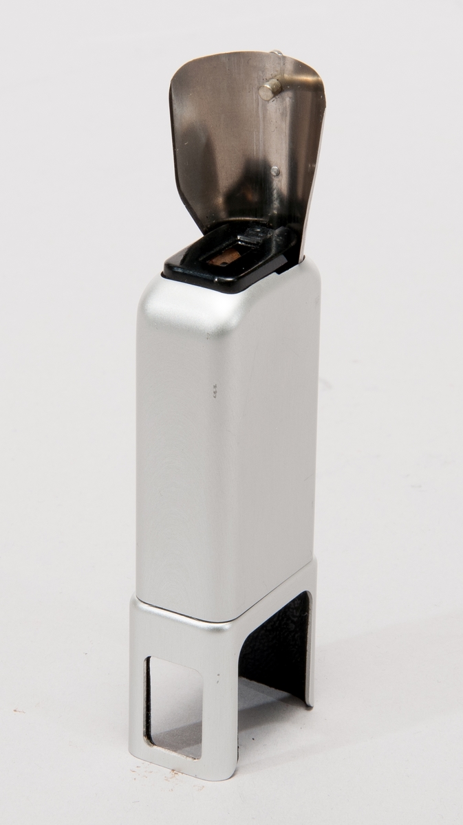 Blixttillsats i aluminium, med plats för batteri. 
Därtill ett stativfäste för minox.
I ask märkt "Minox Blitzgerät Modell B"