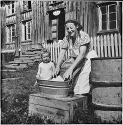 Elen Slupphaug vasker klær og sønnen Nils ser på.