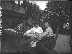 Tre kvinner ved et hagebord utenfor Breidablikk. Fra venstre
