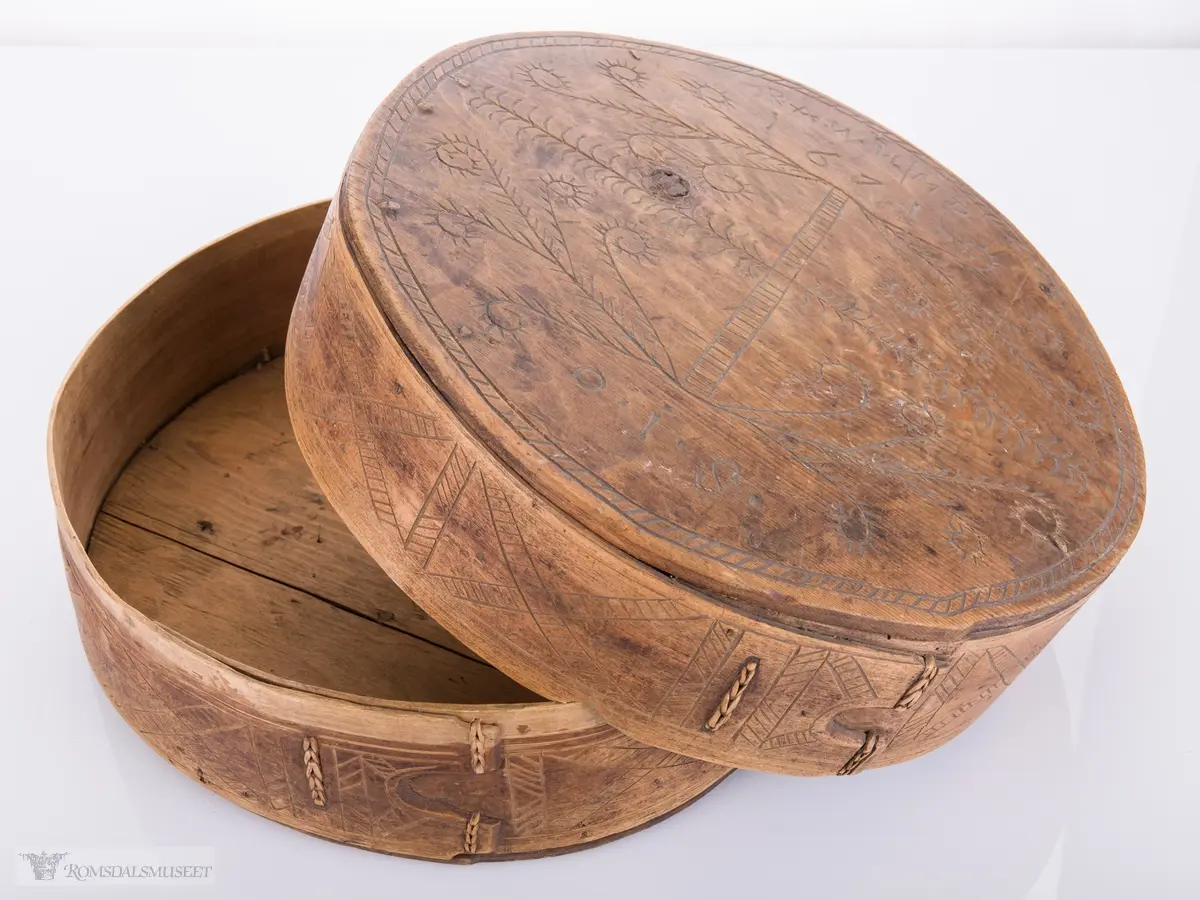 Eit kvistmønster/bregner på lokk. Skravert kryss- mønster langs trosken. Rosett av spetter i bunnen.