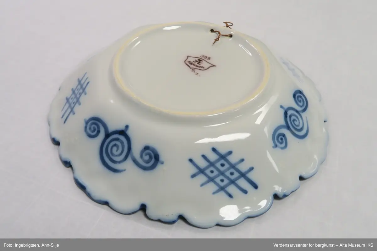 Fat, eller skål, med rund base, og svakt 8-kantet korpus og tunget kant. Motivet i fatet er ornamentalt blomster-, fugle- og sommerfuglmotiv. På baksiden er det motiver av spiraler og ruter.