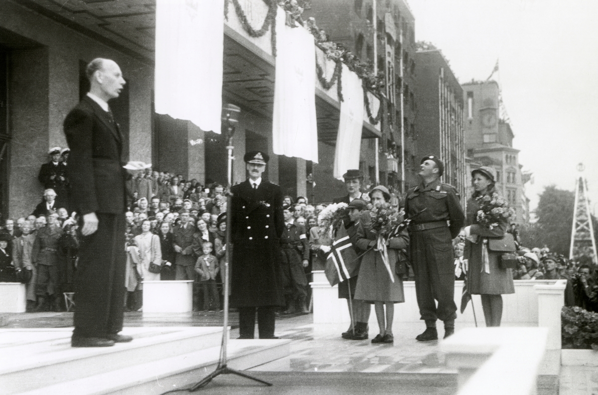 Fra Oslo 7. juni 1945.
Kongen kommer tilbake.Kongefamilien samlet foran Rådhuset.Einar Gerhardsen holder tale.