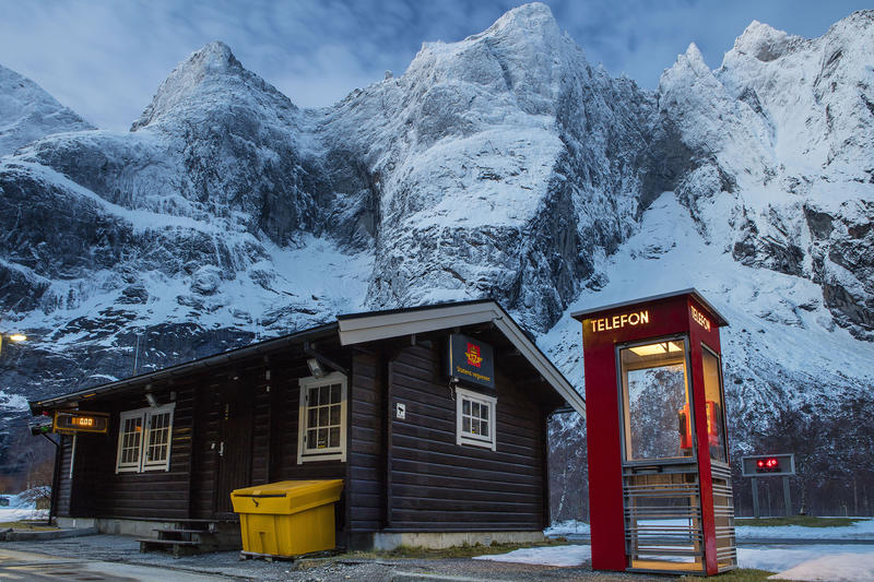 Rød telefonkiosk ved fjell og hus fra vegvesenet (Foto/Photo)
