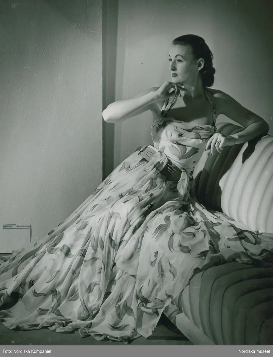 Modell i mönstrad aftonklänning i en soffa.
