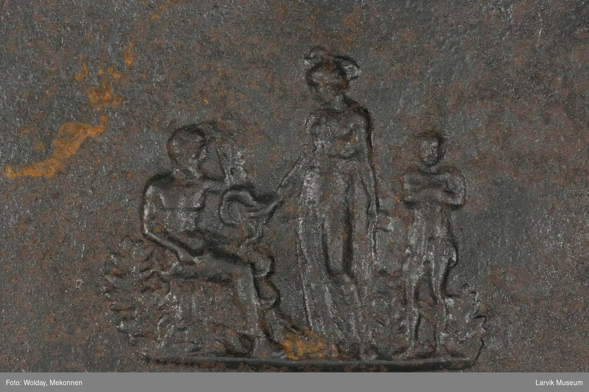 Sittende mann til venstre, stående kvinne i midten og stående barn til høyre.