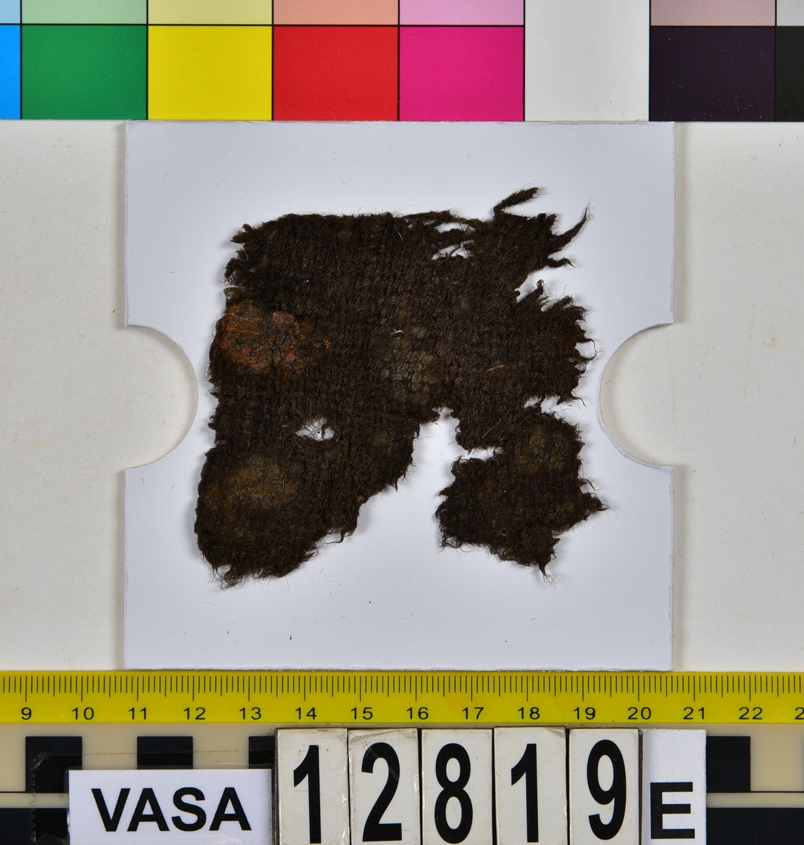 Textilfragment.
34 textilfragment uppdelade på fyndnummer 12819a-h.
Fnr 12819a består av 7 filtade fragment av ull eller bäver.
Fnr 12819b är ett vävt och valkat fragment av ull.
Fnr 12819c är ett fragment av ull vävt i 2/1-kypert samt valkat på ena sidan.
Fnr 12819d består av fyra fragment av ull vävda i tuskaft. Ett av fragmenten har en tydlig originalkant bevarad.
Fnr 12819e består av ett fragment av ull vävt i tuskaft.
Fnr 12819f består av 10 fragment av ull vävda i tuskaft. Ett av fragmenten har en tydlig originalkant bevarad.
Fnr 12819g är två fragment av ull vävda i 2/1-kypert. 
Fnr 12819h består av 8 fragment av ull vävda i tuskaft. Ett av fragmenten har många vävfel (hoppor). Ett av fragmenten har en tydlig originalkant bevarad.