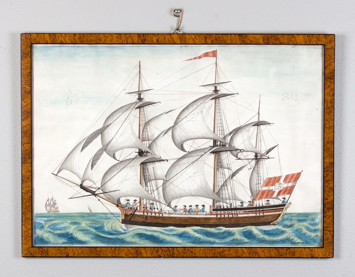 Fullrigger med full seilføring i rom sjø. Skipet sett fra langsiden. Dansk flagg med kongelig monogram i midten i akter, og rød vimpel i masten.