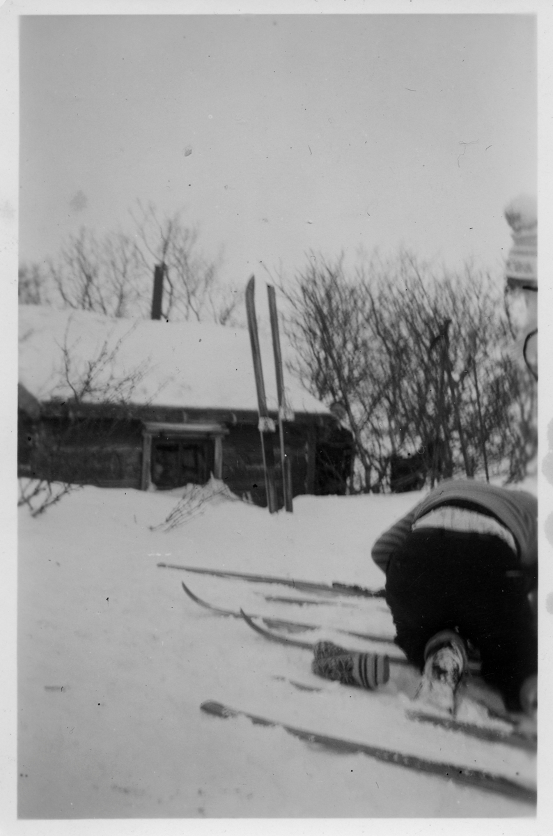 Flere personer utfor hytte på fjellet vinterstid. Det står ski oppstilt i snøen, og flere par ligger på bakken. Antakelig er dette skihytta på Viinikka ovenfor Vadsø by.