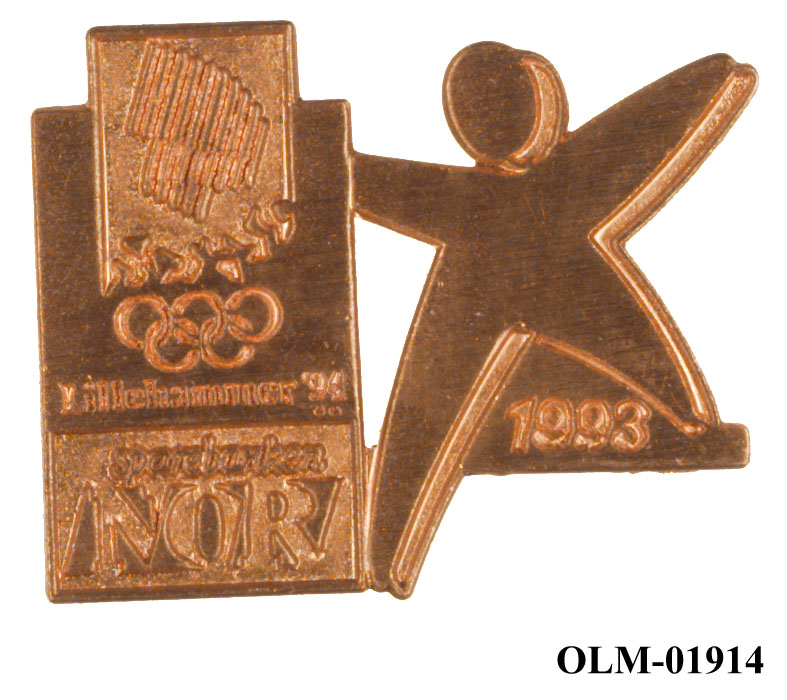 Merke i gullvalør som viser emblemet for Lillehammer '94 og logo for Sparebanken NOR til venstre og logo for "Folk i form til OL" til høyre.