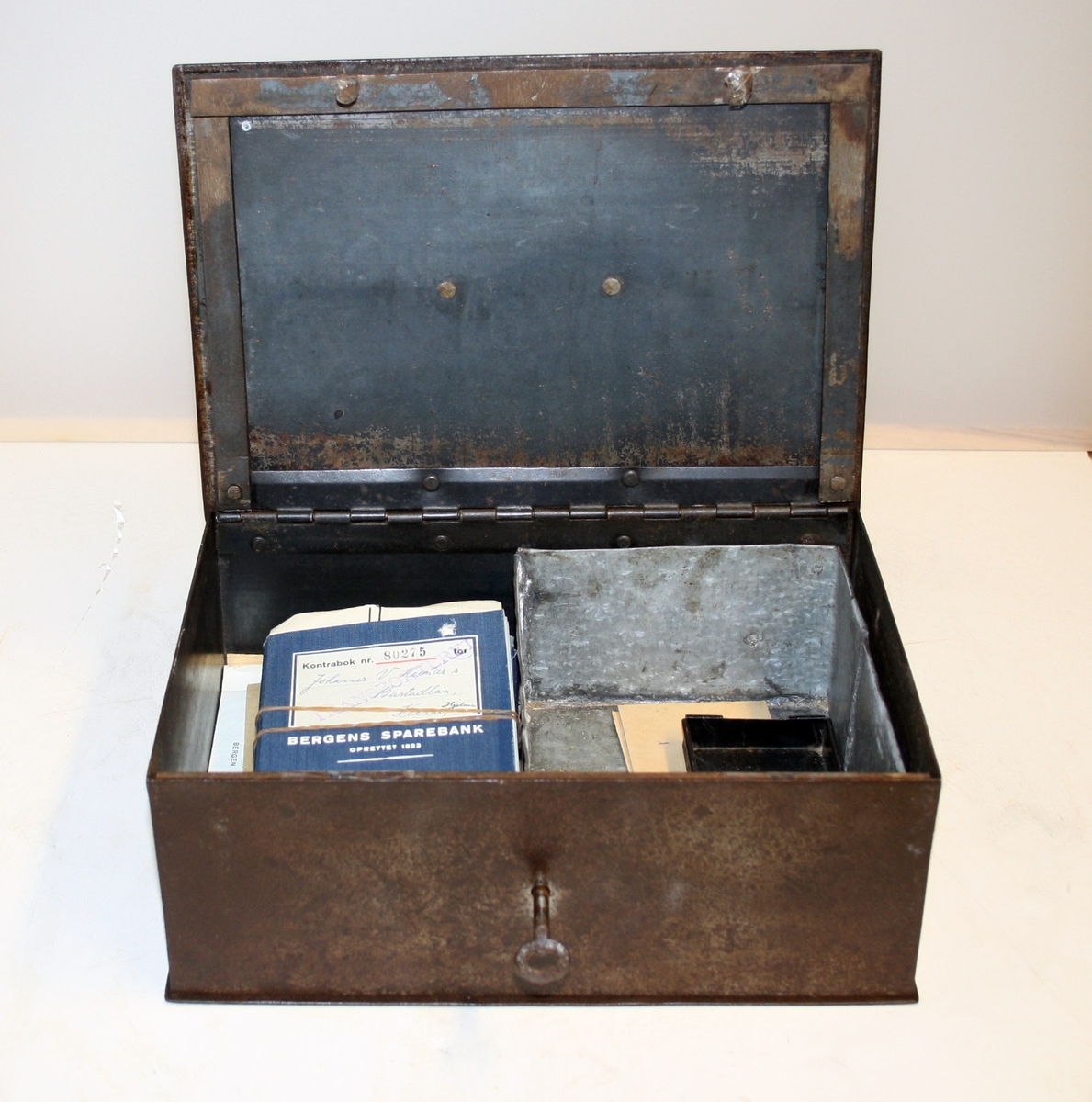 Form: Rektangulært solid stålskrin med lås, handtak og lause behaldarer for sedlar og myntar.
Innhald: 20 stk. avslutta bankbøker og korrespondanse mellom Hjeme kommune og Bergen privatbank.