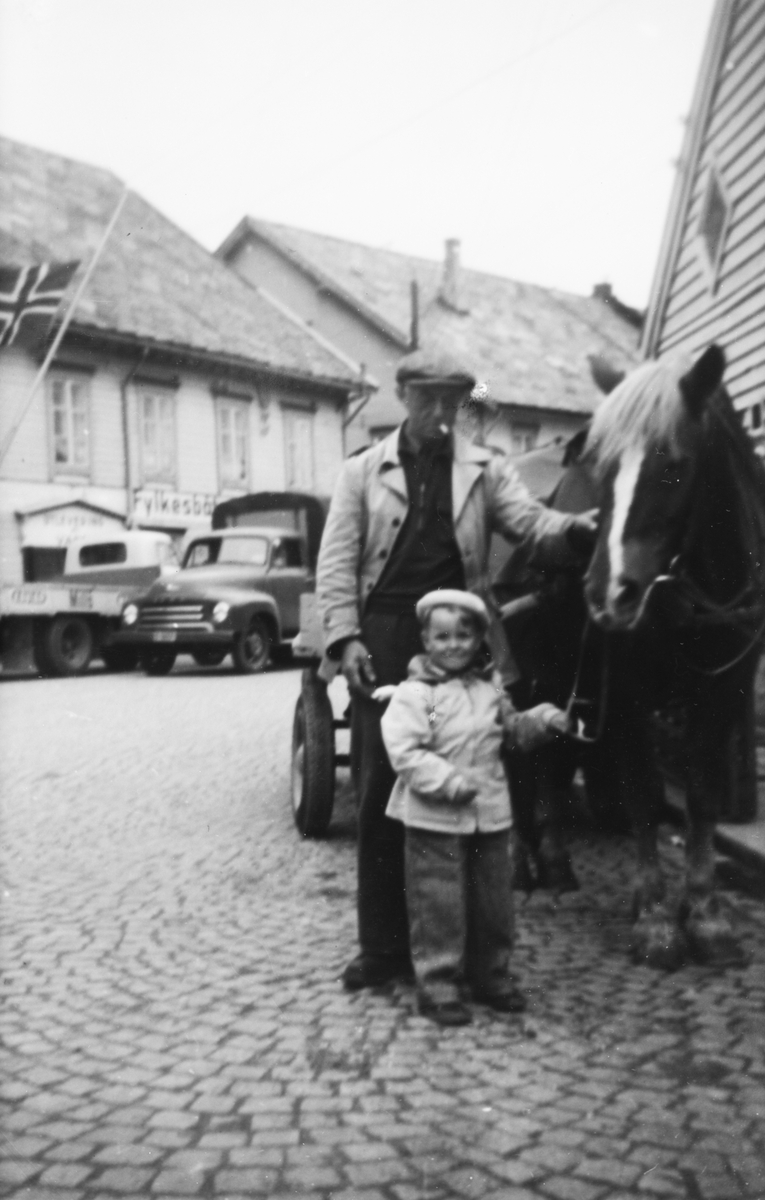 Portrettfotografi av Fredrik Holck og Rosa på Skansekaia. Ved siden av står det en hest med kjerre. I bakgrunnen står to lastebiler foran Fylkesbåtterminalen.