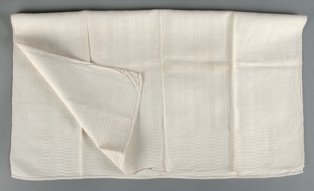 Handduk av vitt halvlinne hemvävd i rutig dräll. Varp av bomull, inslag av lingarn.