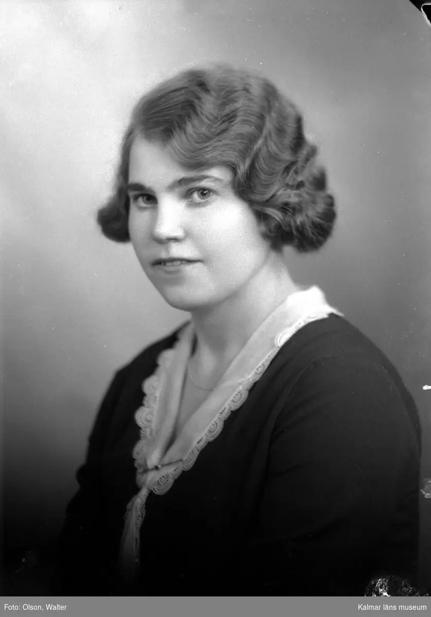 Ateljébild på en kvinna i jumper, spetskrage, brosch och spetskrage. Enligt Walter Olsons journal är bilden beställd av Berta Andersson ifrån Blomkulla.