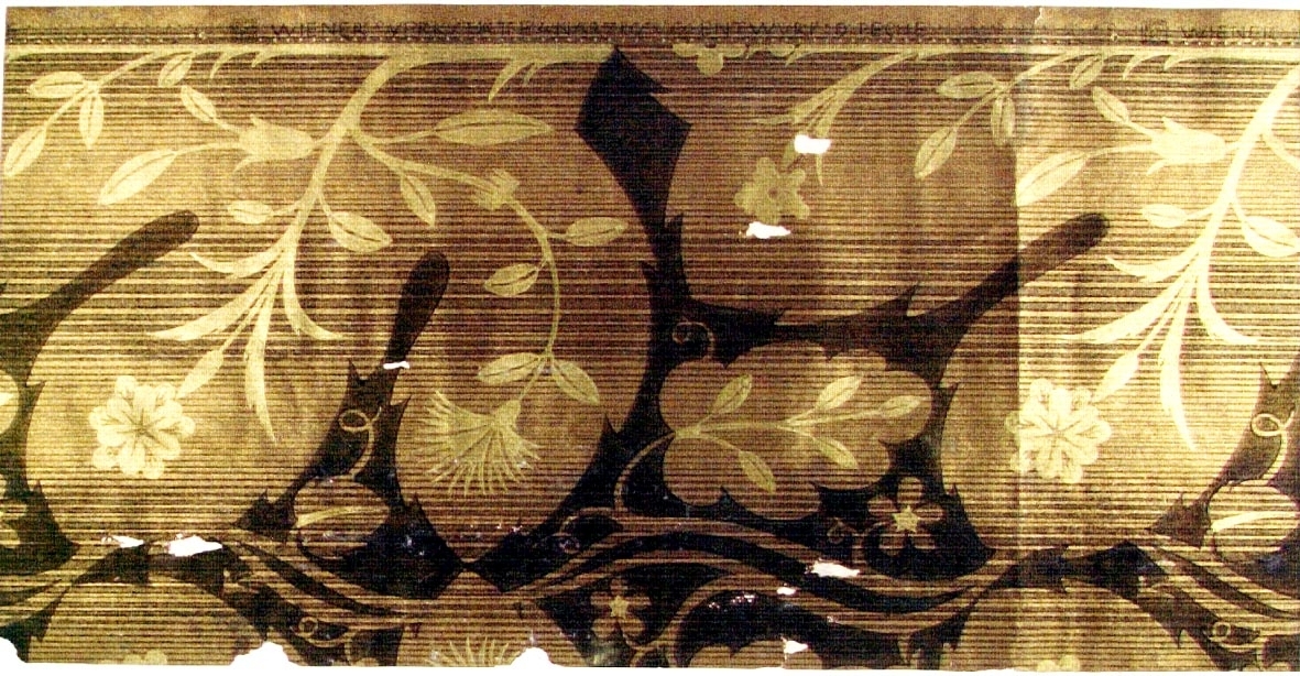 Stort stiliserat växtmönster ovanpå randmönster i guld och kopparton.