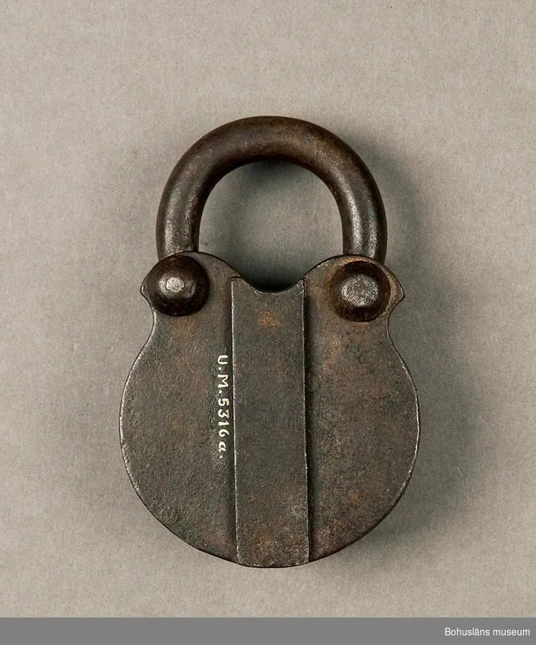 Ur handskrivna katalogen 1957-1958:
Järnlås m. nyckel, hänglås
Låset (A) mått: 11,5 x 7,8 x 3,5 cm; järn; helt. Nyckeln (B) L. 8,2 cm; järn. Något trasig. Föremålen något rostiga.
