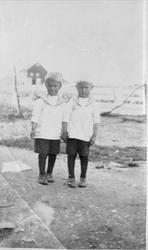 To gutter i matrosdress. I bakgrunnen en fjøs.