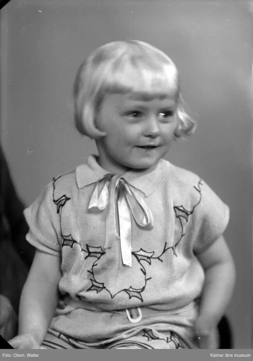Porträtt på ett flicka, med klänning och band.