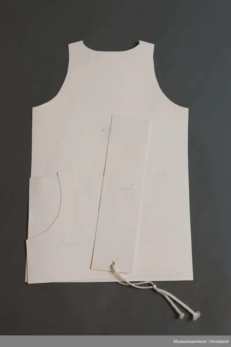 Mønsterskantar i papp, brukt til å skjere ut ulike delar av plagg i klesproduksjon. Desse er til ein singlet.
