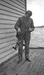 Fangst. En mann står på kaien og viser fram en nyfanget humm