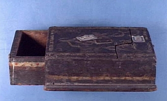 Kassaskrin med utdragbar låda, ena sidans kantlist saknas, lådan låses med fjäderanordning fästad i locket, även lådans sidor målade