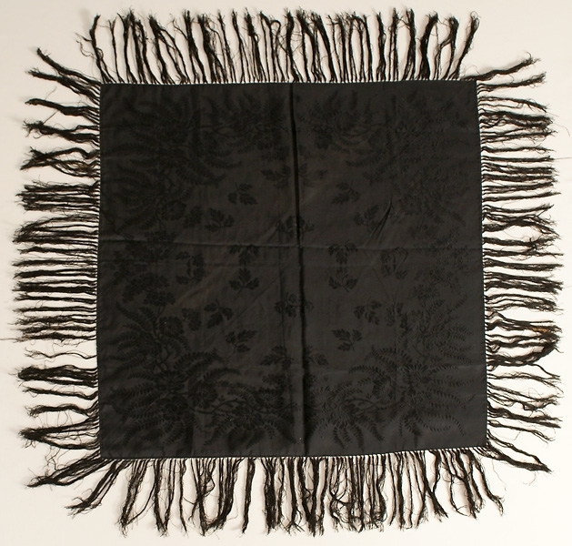 Svart jacquardvävd silkeschal med iknutna fransar, ca 13 cm långa.
Stämplad "K Almgren Stockholm".

Har varit vikt diagonalt, svag blekskada finns