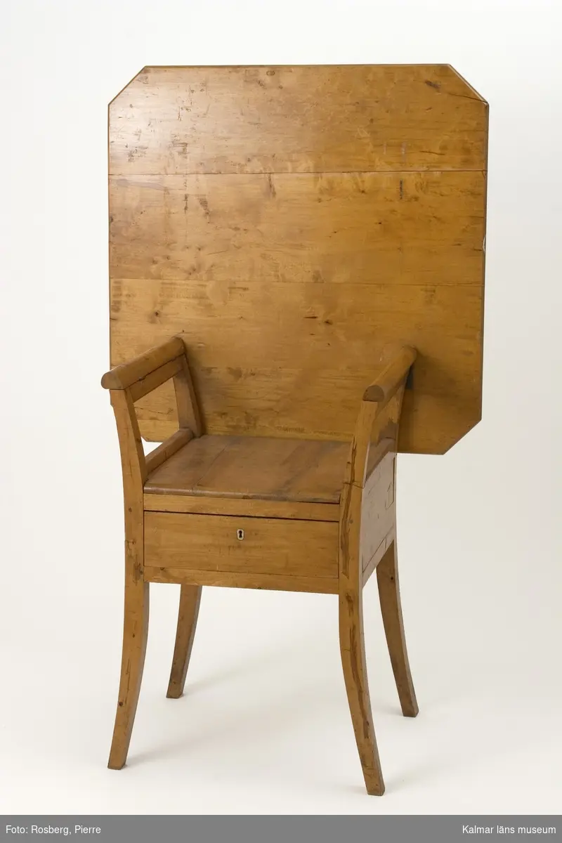 KLM 11177. Stol, bordstol. Av björk med lackad yta. Stol med lätt utsvängda ben. Under sitsen en låda med lås. Kvadratriskt ryggstöd kan kan fällas ned för att fungera som bordsskiva.