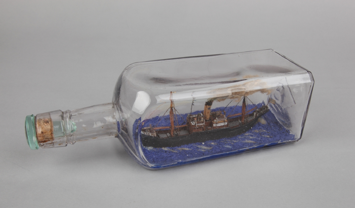 Firkantet flaske med dampskip på meget blått hav, skorsteinsmerke til Didrik Ellerhusen & Co.