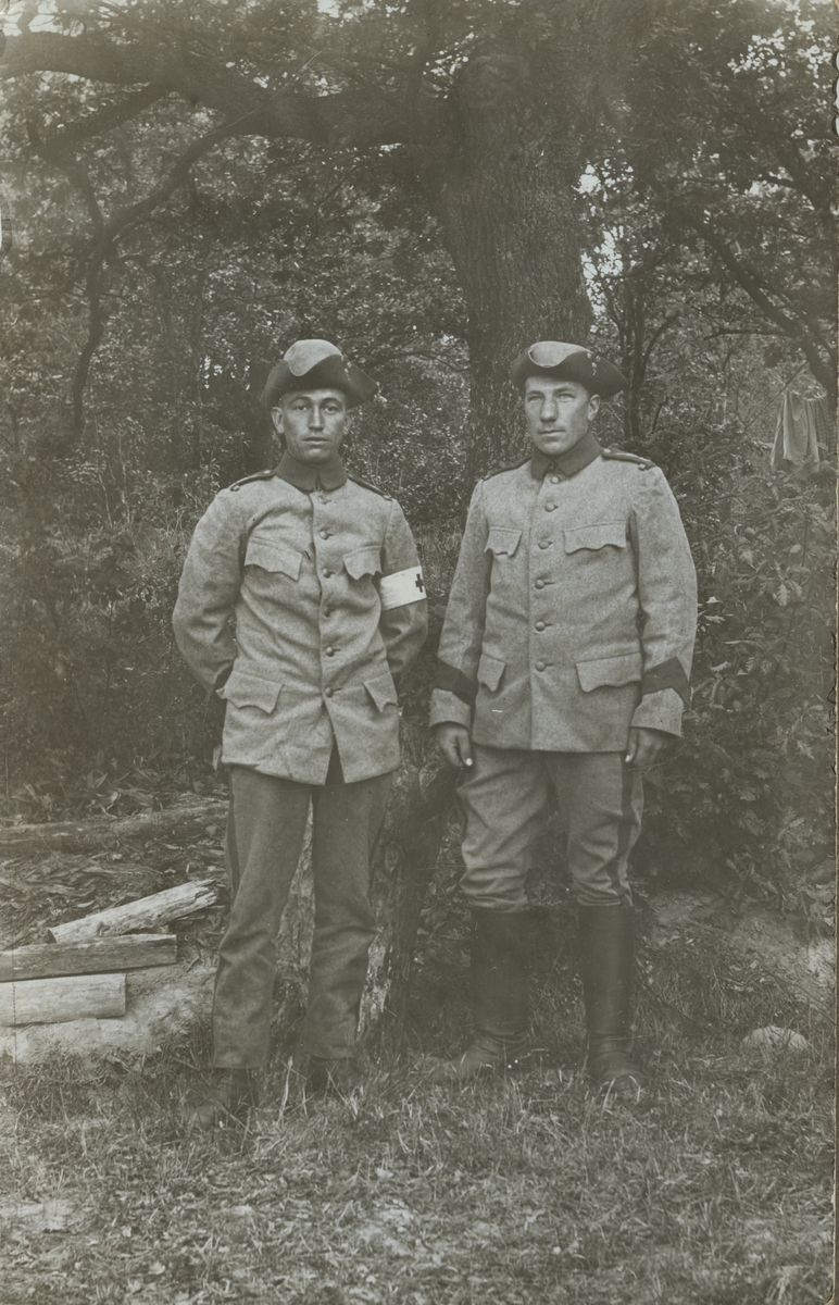 Två soldater vid Positionsartilleriregemente A 9 framför ett träd.