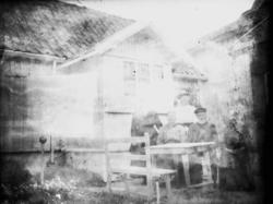 Tre kvinner og to menn ved bord foran bolighus