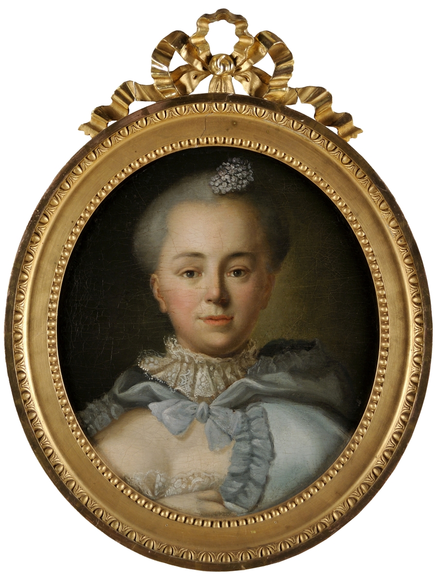 Porträtt, oljemålning på duk, "Damporträtt", troligen av Per Krafft d.ä. Avbildad en face, ljus blågrå klädsel med spetsar kring halsen, liten blombukett i det ljusgråpudrade håret. 
Förgylld ram, oval.
