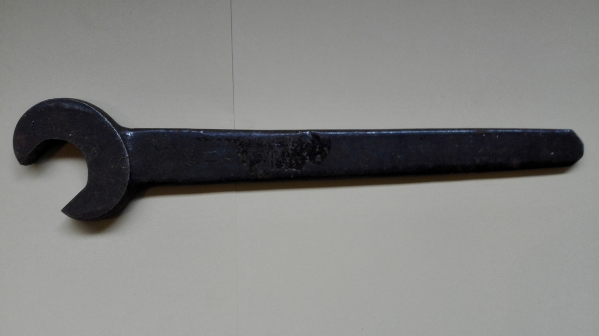 Fastnøkkelen er produsert i eitt stykke stål med ein kjeft i eine enden. Handtaket smalnar av frå kjeften og mot andre enden.