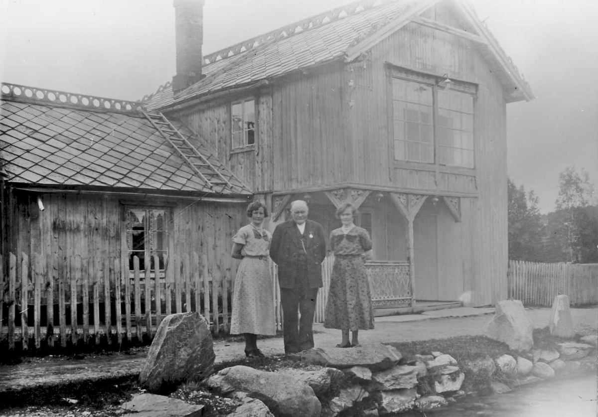 Mann og to kvinner foran bolighus