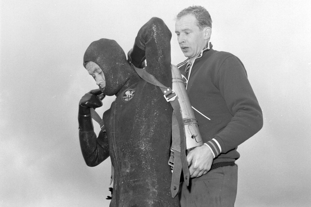 Mann hjelper en dykker på med lufttank.