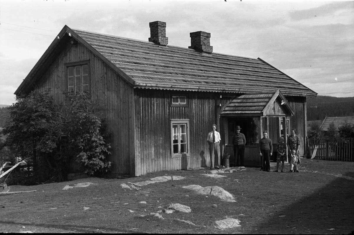 Personer samlet foran våningshuset på småbruket Gårderhagen i Lensbygda, Østre Toten sommeren 1943. Fra venstre: Kåre, Hans og Leif Gårderhagen, Sigrun Røisli, og Karine Røisli med sønnen Kjell foran seg.