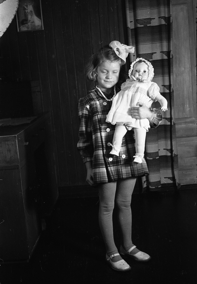 Portrett av en uidentifisert jentunge med dukke. Serie på sju bilder.