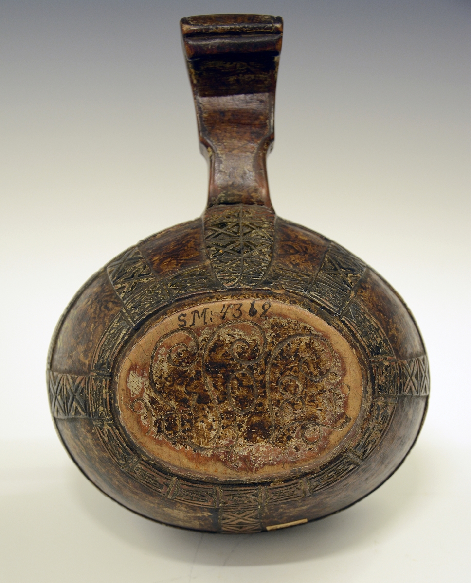 Øløse i tre. Fra protokollen: Øse fra 1806. Under bunden skaaret JTS 1806. Bladorn. paa skaftet. Utenpaa baand av kerbsnitruter, indelt i 4 kanter. Rundt kanten oppe, nede og 5 paa tvers og ett dobbelt ved skaftet.