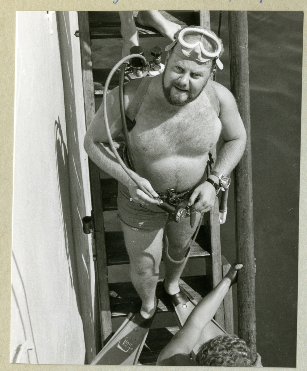 Bilden föreställer en besättningsman i dykarutrustning under minfartyget Älvsnabbens långresa 1966-1967.