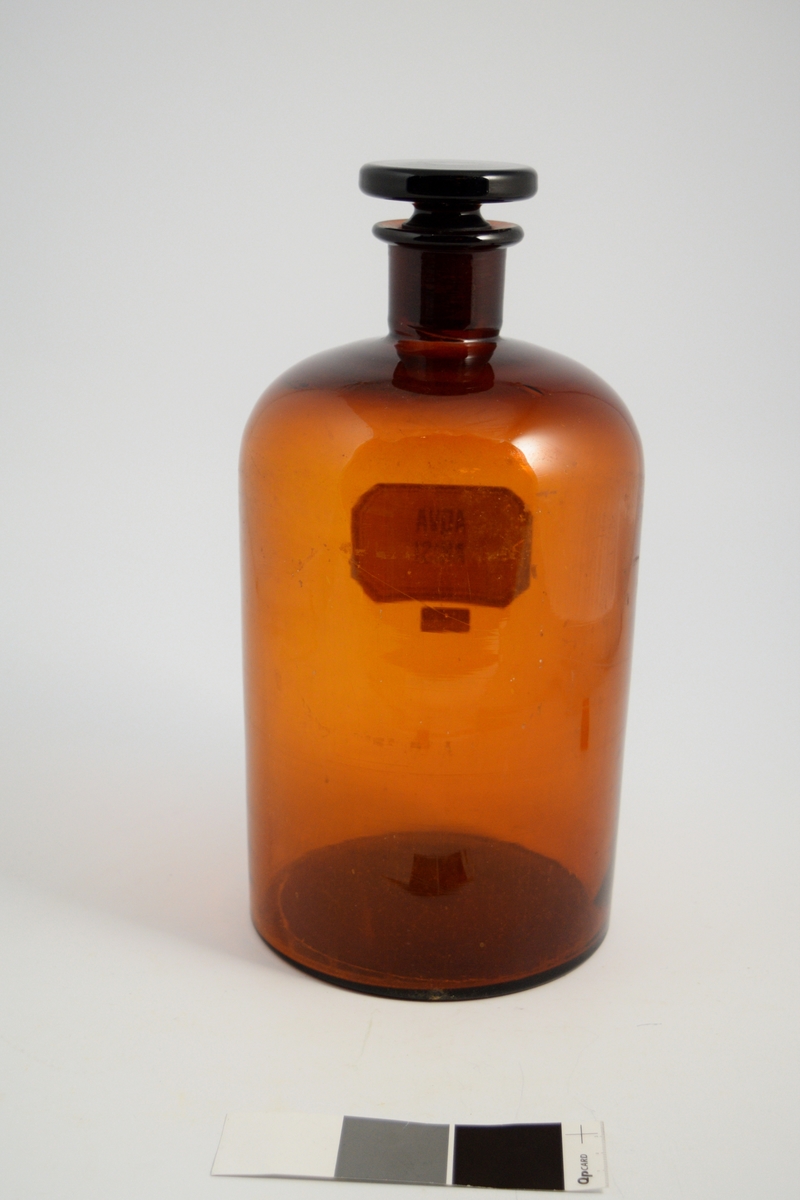 Brun glassflaske, smal hals, brun glasspropp. Påført hvit etikett med sort skrift. Flasken brukes til oppbevaring av løsninger. Anisvann ble brukt som smakstilsettning.
