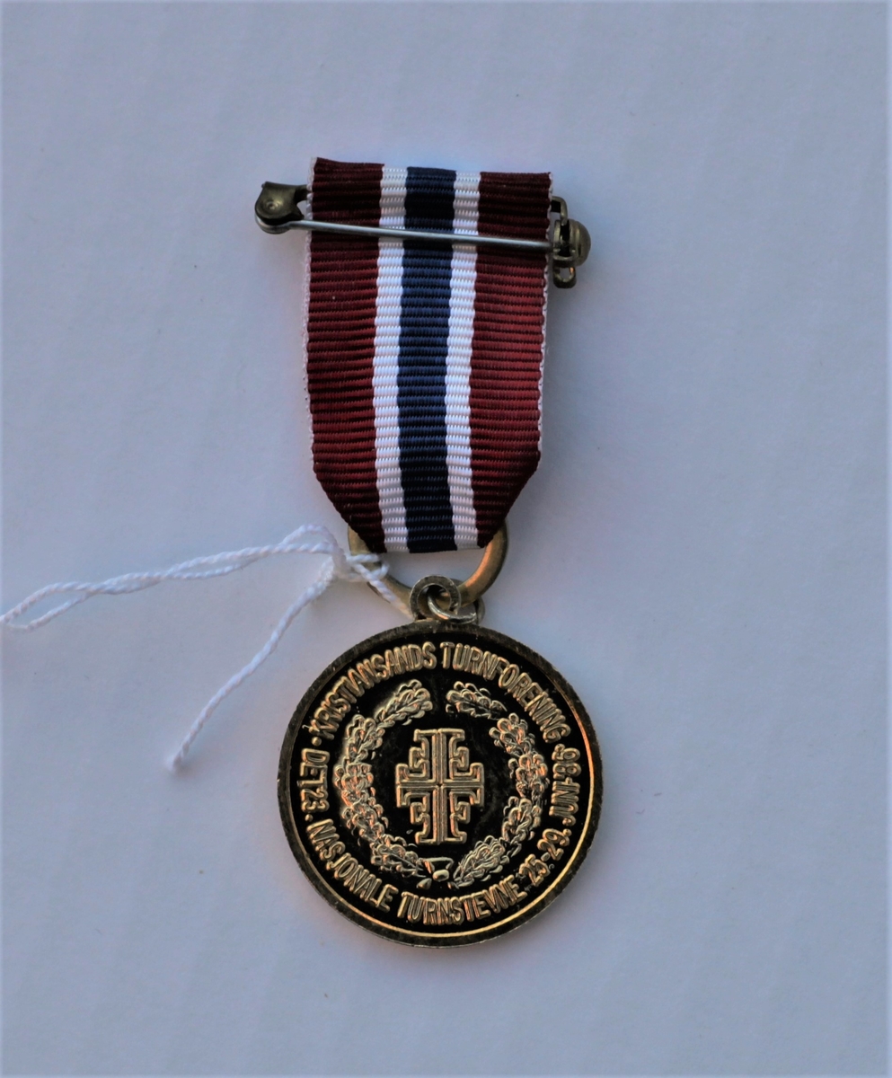 Rund medalje med festebånd i Norges nasjonalfarger.