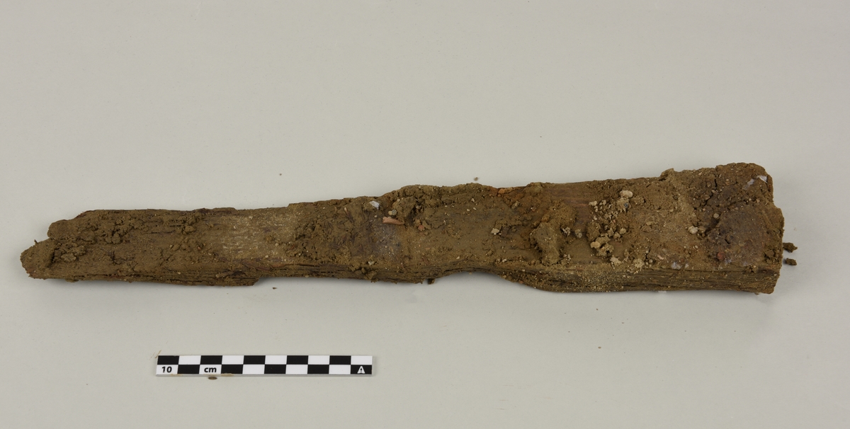 Deler av en rektangulær gravkiste.
Det er 4 avlange rektangulære treplanker og tverrplanker fra kisten. Hver er laget av ett stykke tre. Det er rester etter spiker og misfarging på grunnen av rust.