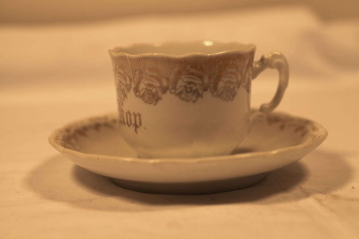 Kopp og skål i hvit porselen med gulldekor. Innskrift: Mors kopp. Gammelt nr: 2565c