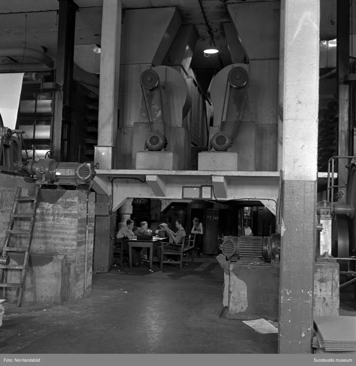 Interiör- och exteriörbilder samt personal vid Östrands pappersbruk. På första bilden är det ett arbetslag som har lunchrast.